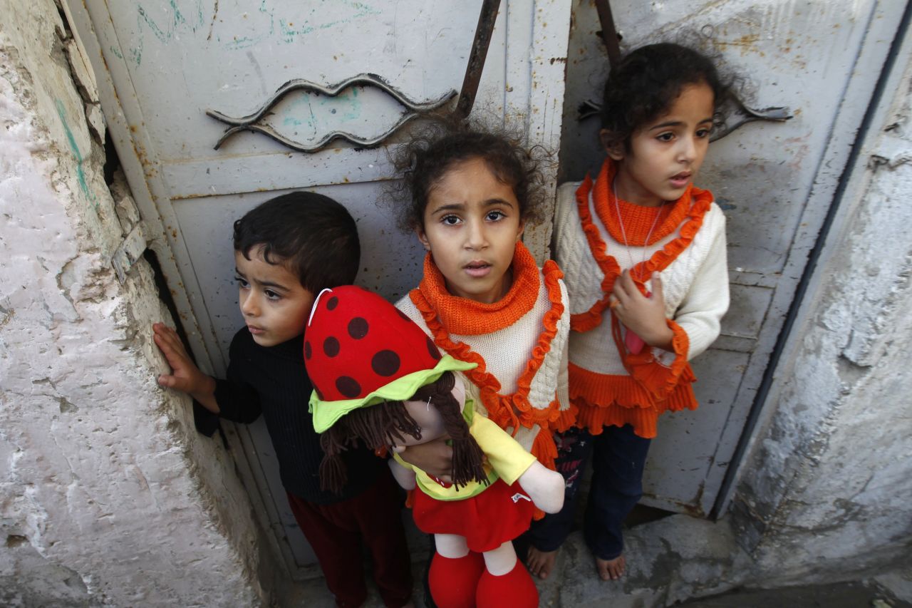 Palestinian children stand at the gate of their home Tuesday as they watch a funeral procession for those killed following an Israeli airstrike in northern Gaza.  