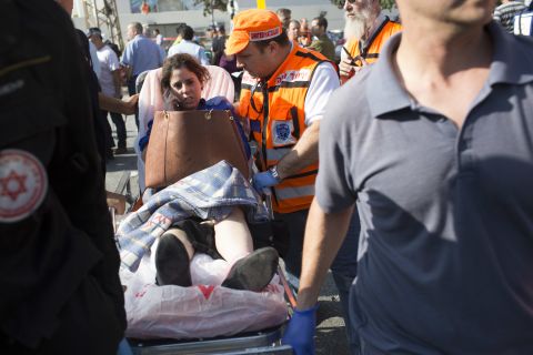 A woman is helped at the scene by emergency workers Wednesday after the explosion on the bus in Tel Aviv.