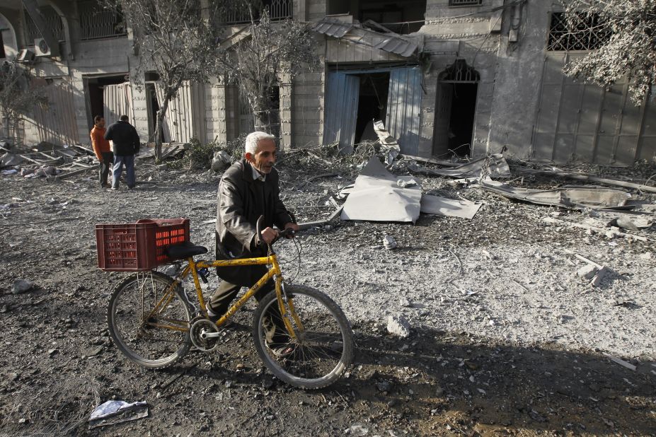 A Palestinian pushes his bicycle amid debris Wednesday near the destroyed compound of the Ministry of Internal Security in Gaza City. An Israeli airstrike targeted the building overnight.