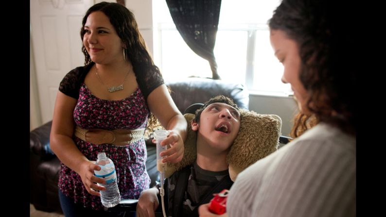 Mimi feeds Isaac while their mother, Rose Santiago, looks on. Often, Siskowski says, young caregivers find themselves overburdened by the extra responsibility and fall behind in school. They can also feel depressed, anxious and isolated.