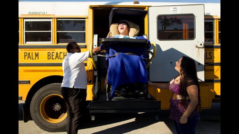 Mimi waits to greet Isaac as he is lowered down from the bus he rides to school.