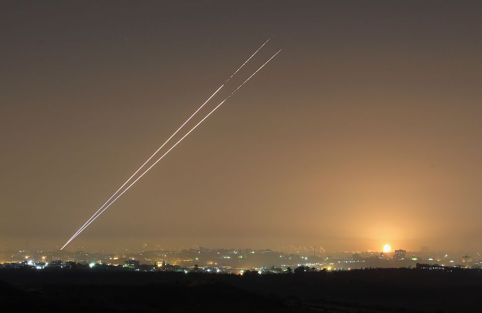Rockets launch from Gaza City as an explosion is seen on the horizon at Israel's border with Gaza on Wednesday. 