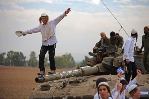  A Hasidic Jewish boy dances on the barrel of a tank Thursday as he and others celebrate the Israeli soldiers.