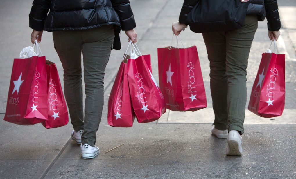 Women carry Macy's bags down 34th Street after shopping the Black Friday sales.