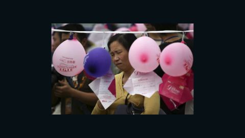 A woman looks at notes hung on balloons by single men and women who hope to meet members of the opposite sex in Chongqing, China on Singles Day.
