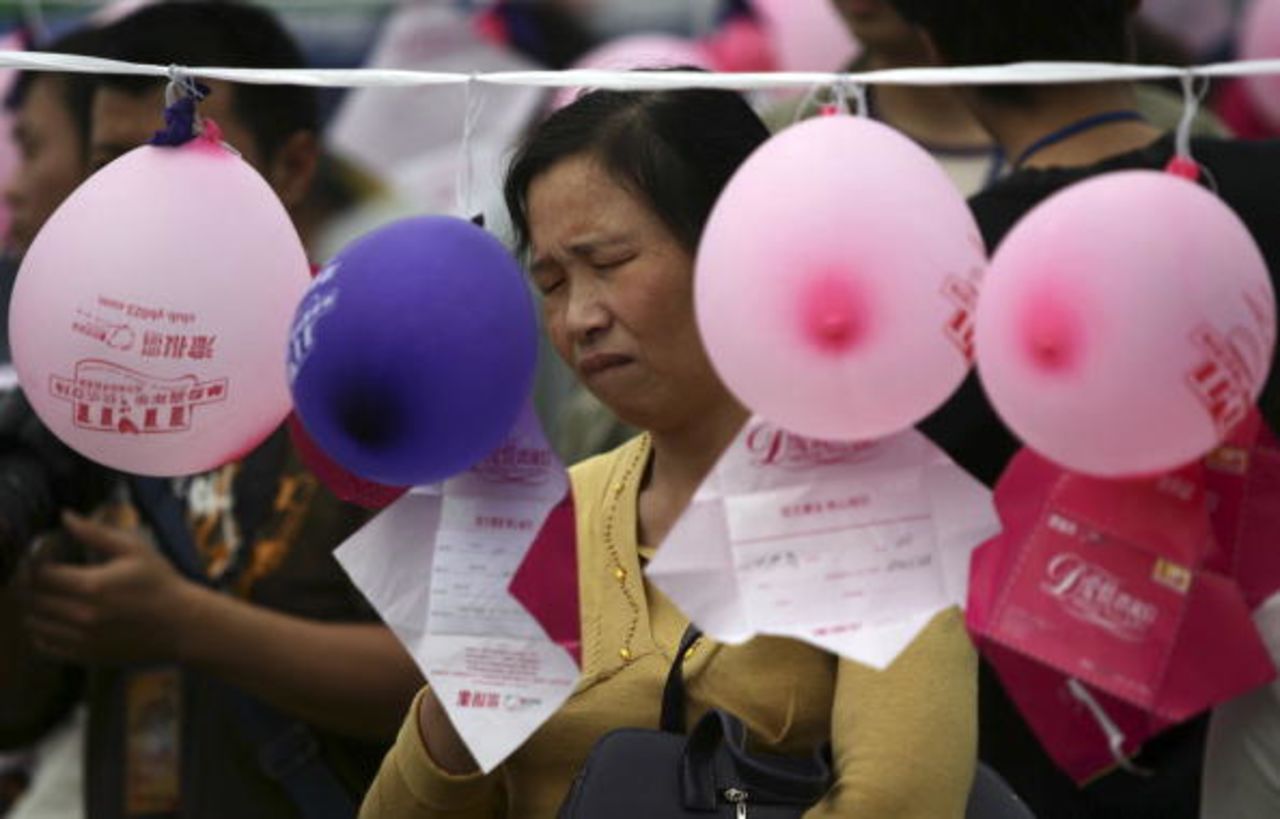 A woman looks at notes hung on balloons by single men and women who hope to meet members of the opposite sex in Chongqing, China on Singles Day.