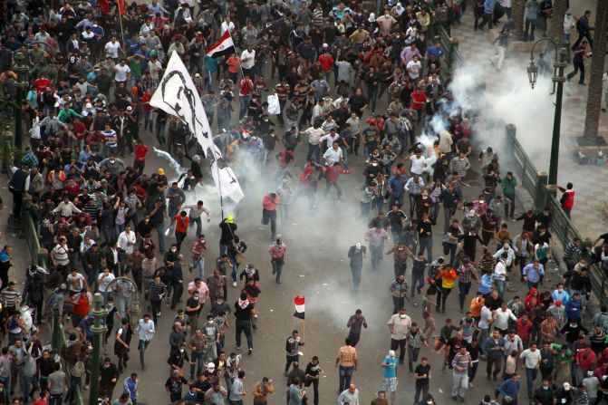 Protesters demonstrating against Morsy run from tear gas fired by Egyptian riot police during clashes in Cairo's Tahrir Square on Friday.