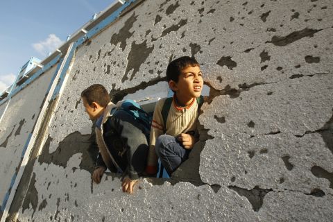 Palestinian schoolboys look through a hole at their damaged school in Gaza City on Saturday.