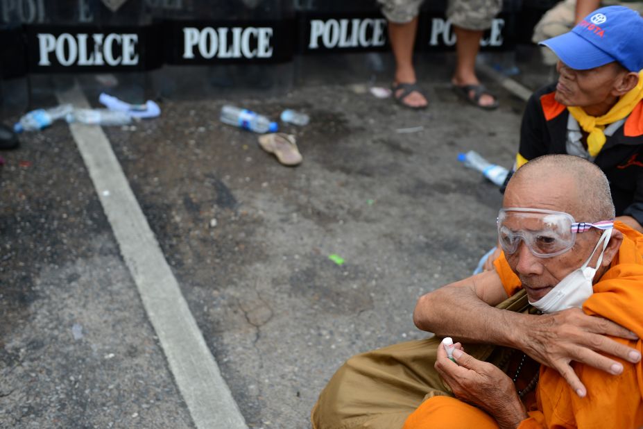 A Thai Buddhist monk sits in front of riot police officers as he takes part in the protest on Saturday.  Thai police fired tear gas and detained dozens of demonstrators as clashes erupted at the first major street protests against Prime Minister Yingluck Shinawatra's government. 