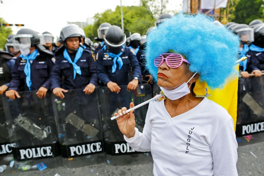 An anti-government protester walks past ranks of Thai riot police on Saturday.
