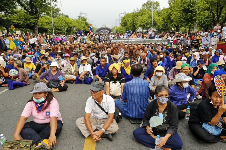 Protesters and Buddhist monks sit on the ground in front of riot police during a protest on Saturday.