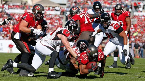 Running back Doug Martin of the Buccaneers dives for extra yardage as defender Robert McClain of the Falcons brings him down on Sunday.