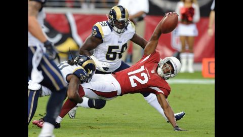 Andre Roberts of the Cardinals dives forward with the ball while being tackled by Janoris Jenkins of the Rams on Sunday.