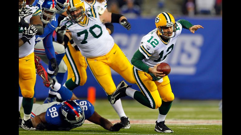 Quarterback Aaron Rodgers of the Green Bay Packers gets tripped up by No. 99 Chris Canty of the New York Giants on Sunday.