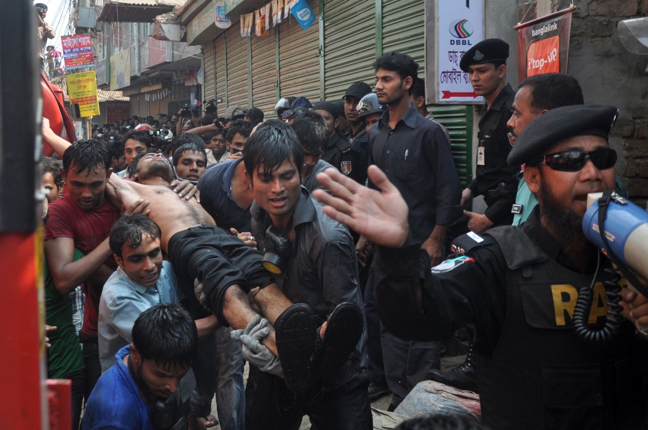 Bangladeshi firefighters carry an injured man from the fire on November 26.