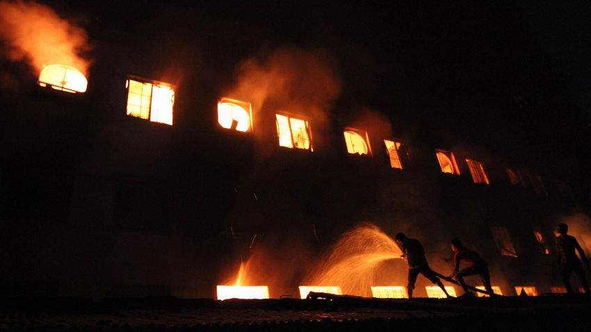 This picture taken on 24 November, 2012 shows Bangladeshi people and firefighters trying to extinguish a fire in a garment factory in Savar, 30 kilometres north of Dhaka. The death toll from a fire at a Bangladeshi factory soared to at least 121 as rescue workers recovered 112 bodies on November 25, the national fire chief told AFP. AFP PHOTO (Photo credit should read STR/AFP/Getty Images)