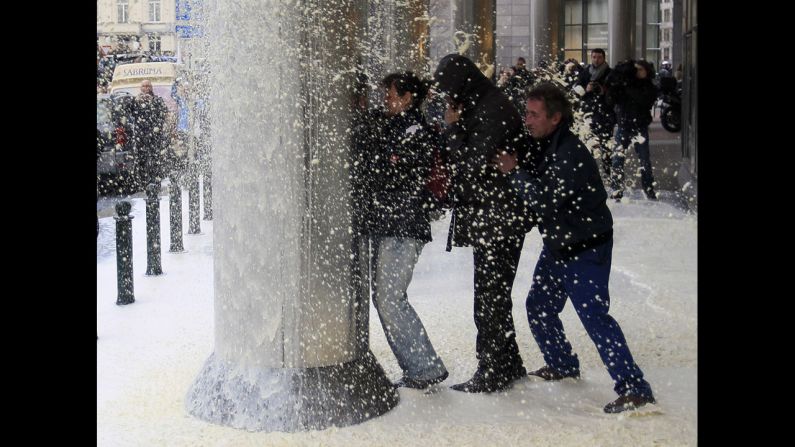 People shield themselves from the spray of milk in front of the European Parliament on Monday.