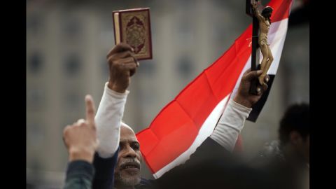 An Egyptian protester holds up a Quran and a figure of Christ on the cross during Tuesday's demonstration.