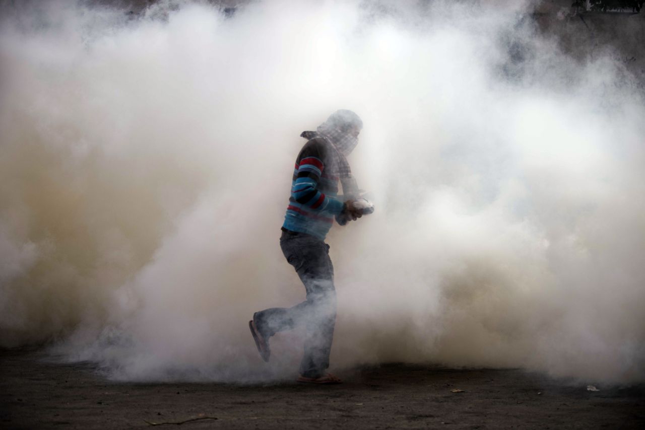 An Egyptian protester attempts to throw back a tear gas canister on Tuesday during clashes with riot police in Omar Makram Street, off Tahrir Square.