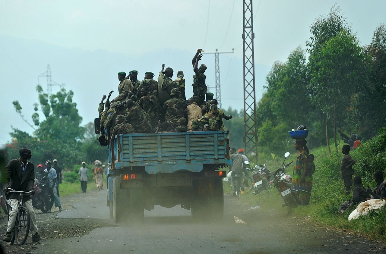 Guerrilleros del movimiento rebelde M23 montan en la parte trasera de un camión, cruzando un campamento de desplazados internos en Mugunga, República Democrática del Congo, el 24 de noviembre de 2012.