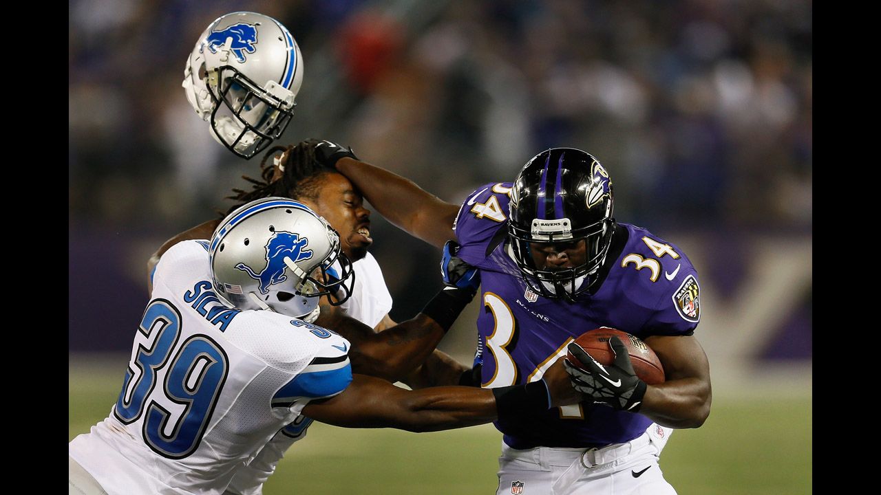 Jonte Green of the Detroit Lions loses his helmet while being stiff-armed by Bobby Rainey of the Baltimore Ravens as Ricardo Silva tackles him on August 17 in Baltimore, Maryland.