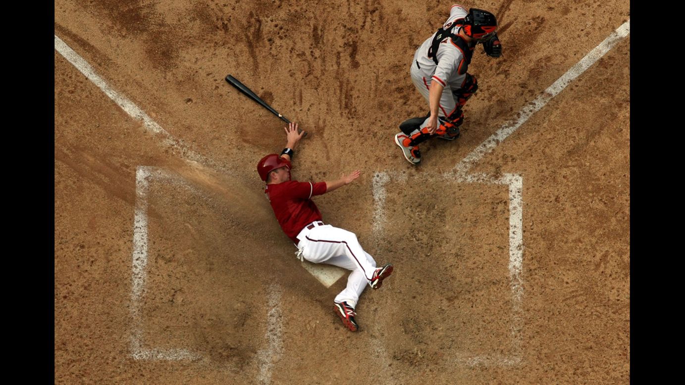 Aaron Hill of the Arizona Diamondbacks safely slides in to score a run past catcher Buster Posey of the San Francisco Giants at Chase Field on April 8 in Phoenix. The Diamondbacks defeated the Giants 7-6.