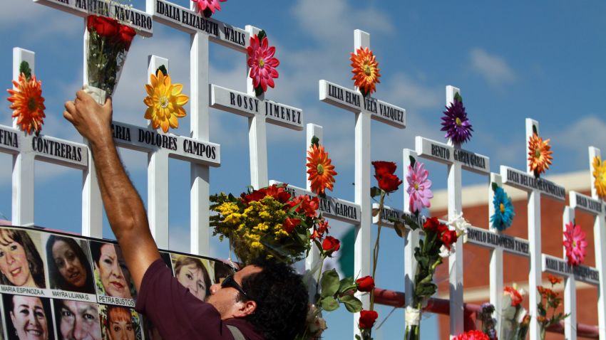 A relative of victims of the Casino Royale puts flowers on a cross during the commemoration of the first anniversary of the crime in Monterrey, Mexico, on August 25, 2012. 52 people died on August 25, 2011, when members of Los Zetas drug cartel doused the Casino Royale with gasoline and set it ablaze.