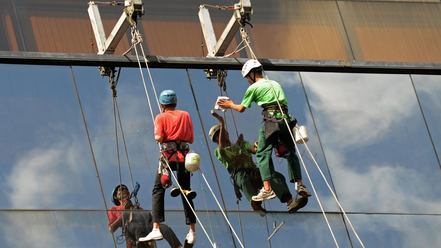 Workers clean windows of a building in Manila on November 28, 2012.