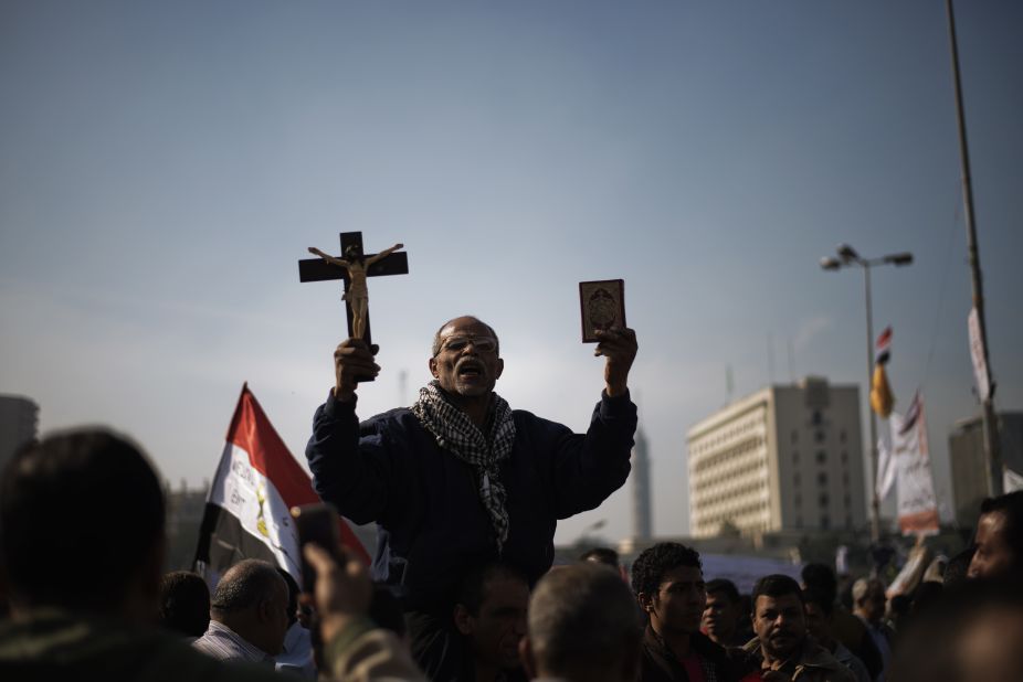 A man holds a copy of the Quran and a cross in Tahrir Square on November 30.