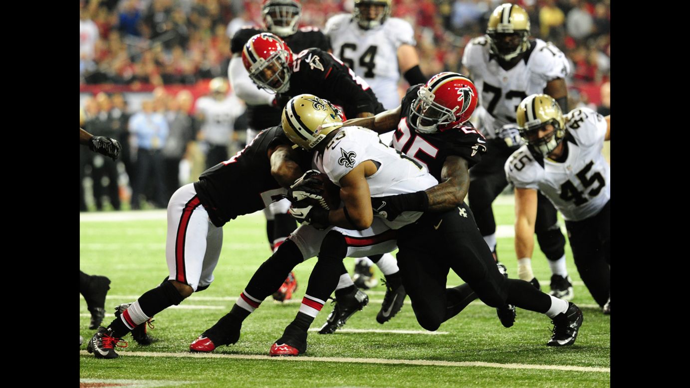 Pierre Thomas of the New Orleans Saints gets a face mask tackle by William Moore of the Atlanta Falcons during a run on Thursday, November 29, 2012, at the Georgia Dome in Atlanta.