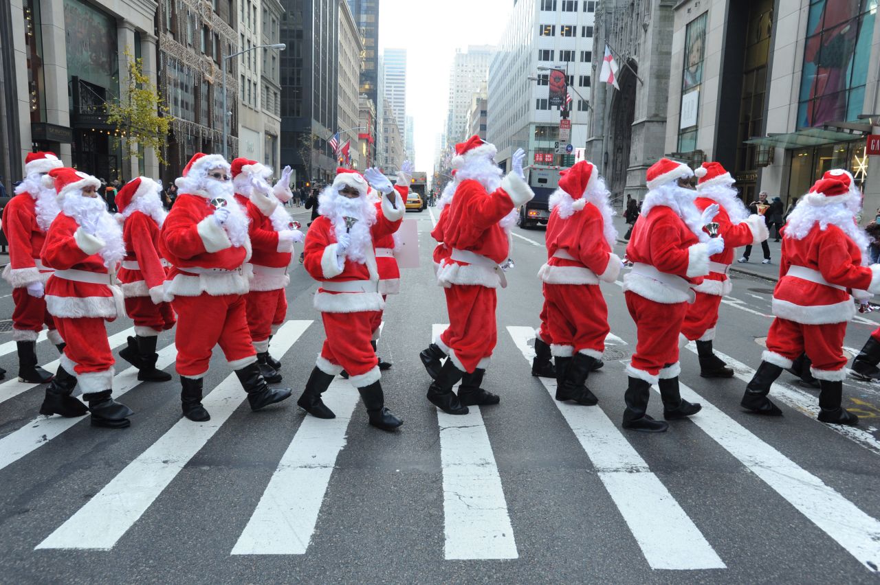 Volunteers in New York's 110th annual Sidewalk Santa Parade cross the street on Friday, November 23.