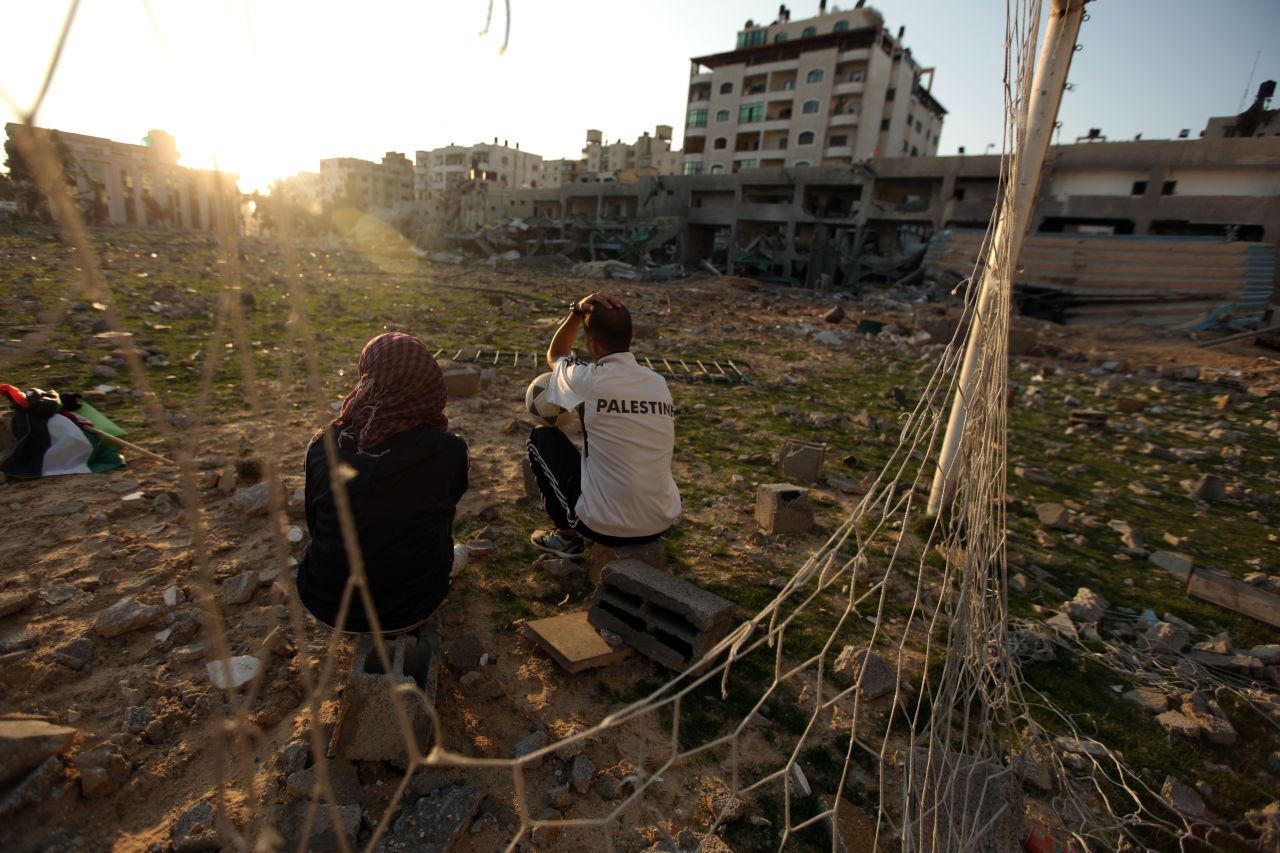 Bilal Abu Samaan (right) and Ala Ayoub sit in the rubble of the bombed stadium.