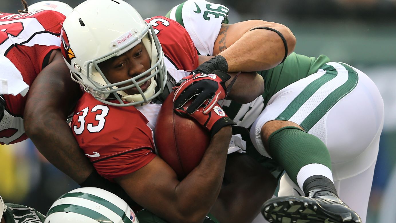 William Powell of the Arizona Cardinals is stopped by Lex Hilliard of the New York Jets in the first quarter on Sunday.