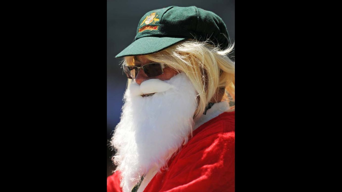 A spectator dressed as Santa Claus and wearing an Australian green cap watches the South African team walk out onto the field at a cricket match against Australia on December 3.