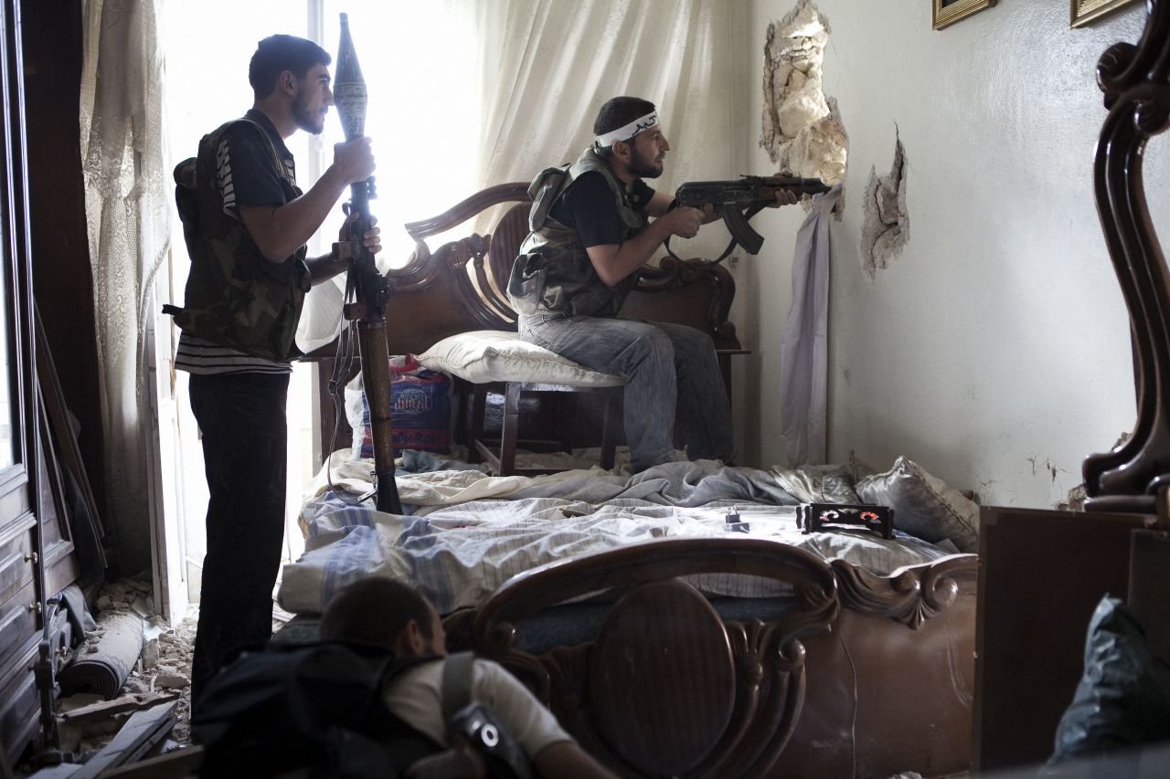 <strong>October 19:</strong> Free Syrian Army fighters watch a regime army position through a hole in a wall in Aleppo, Syria's most populous city..