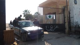 Syrian rebel fighters drive through the gate of the Syrian Government army Base 46 after its capture, near Aleppo, on November 21, 2012