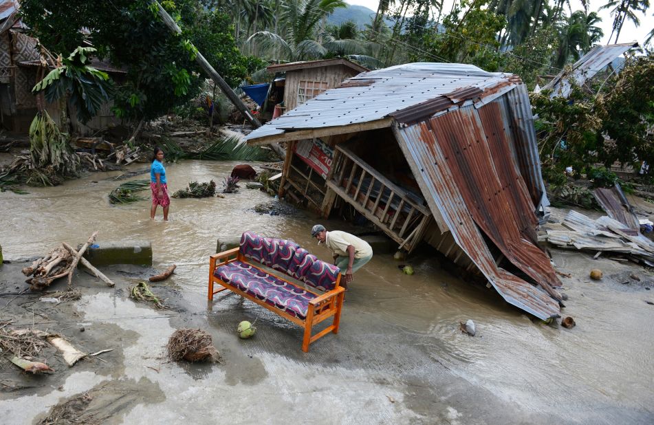 Residents clean their sofa next to their damaged house in New Bataan township on December 5.