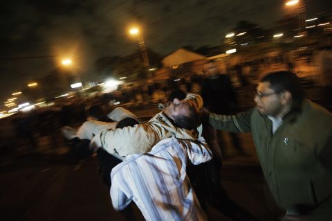 Morsy supporters carry an injured man to safety during clashes with anti-Morsy demonstrators on a road leading to the Egyptian presidential palace on December 5.