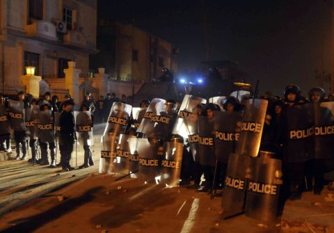 Riot police form a line as anti-Morsy protesters surge around the Muslim Brotherhood's headquarters in Cairo on December 6.