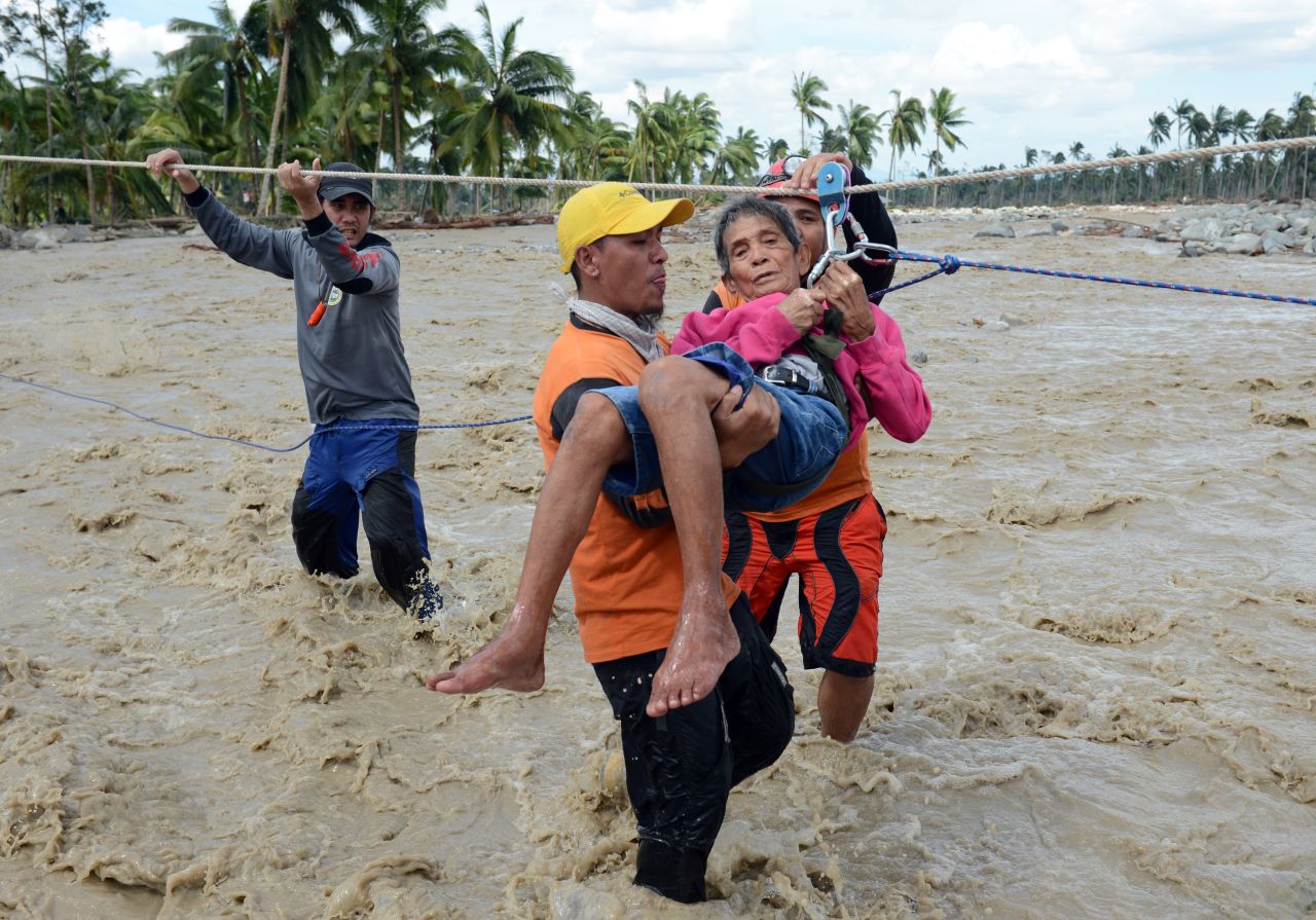 A rescue worker carries an elderly resident across a surging river in New Bataan on December 6.