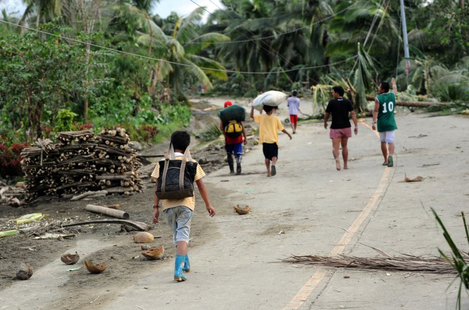 Residents walk down a road covered in debris after the storm in New Bataan on December 5.