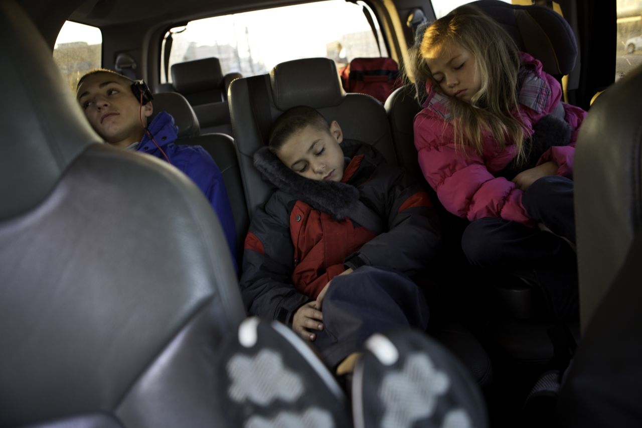 Tim, 15, Christian and Carly rest on their way to a bus that will take them to school. Their family has temporarily relocated from Broad Channel section of Queens to an apartment in Brooklyn. 
