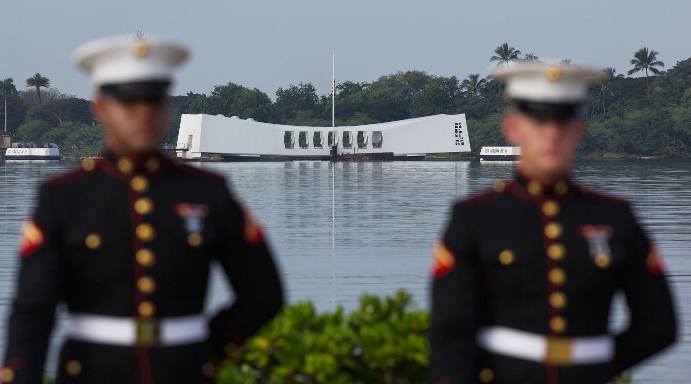 A U.S. Marine firing detail stands at attention with the Arizona Memorial in the background in Pearl Harbor, Hawaii.
