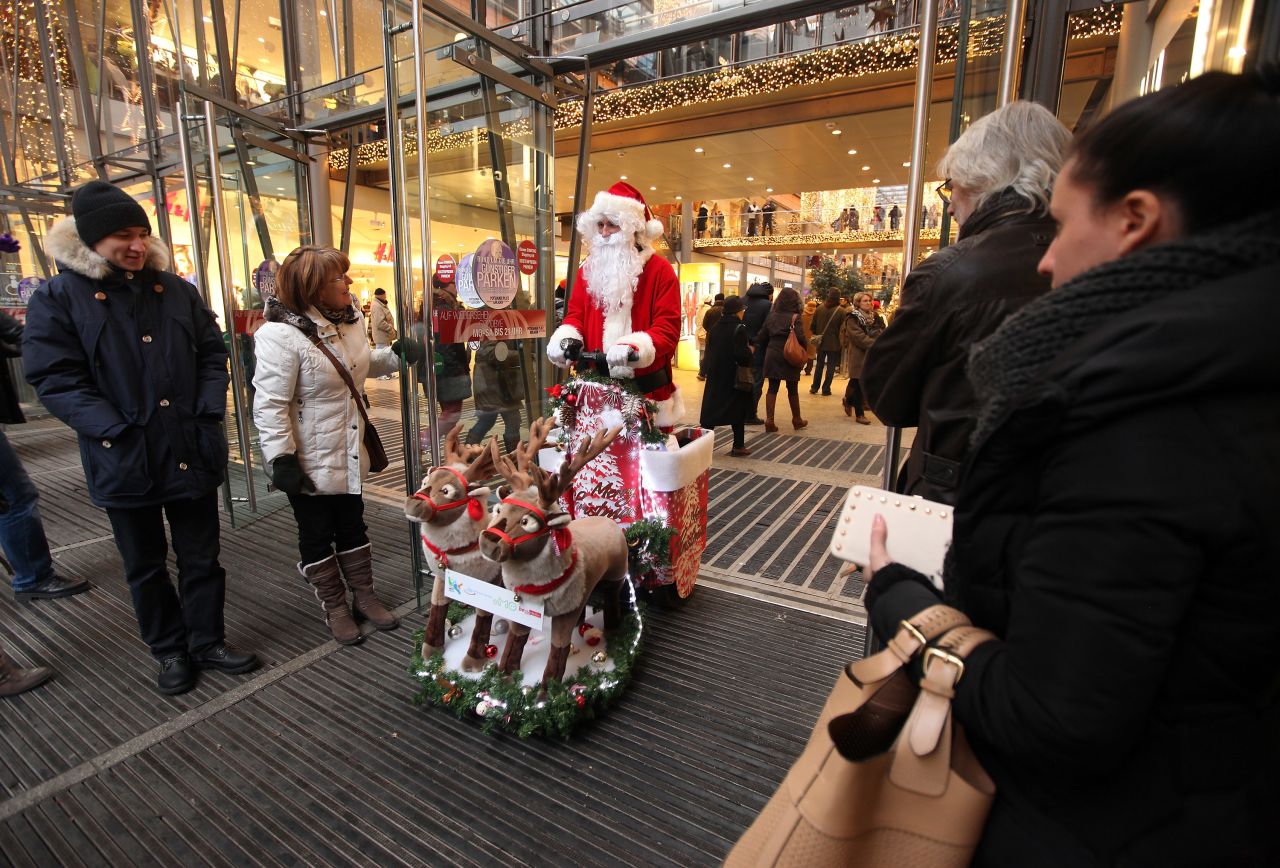 A customer holds the door of a shopping mall for a man dressed as Santa Claus on December 8, in Berlin.