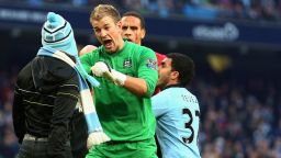 Manchester City goalkeeper Joe Hart of  confronts a pitch invader at the end of his side's 3-2 derby defeat by Manchester United, whose defender Rio Ferdinand (at back) was left with a bloody face after being hit by a coin thrown from the crowd. 