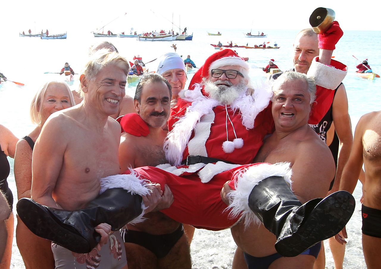 Beachgoers carry a man wearing a Santa Claus costume on the Mediterranean coast on Saturday, December 8, in Nice, France. 