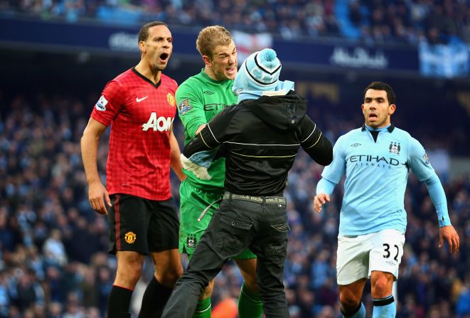 Manchester City goalkeeper Joe Hart confronts a pitch invader trying to harass Manchester United's Ferdinand, who had been hit in the face by a coin thrown from the crowd. 
