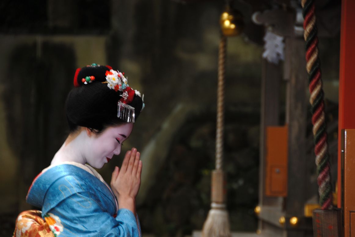 A maiko (apprentice geisha) rings a bell at a temple in Kyoto. As the clock ticks toward 2013, temples across the city will ring large bronze bells 108 times, a Buddhist tradition said to rid humans of earthly desires. 