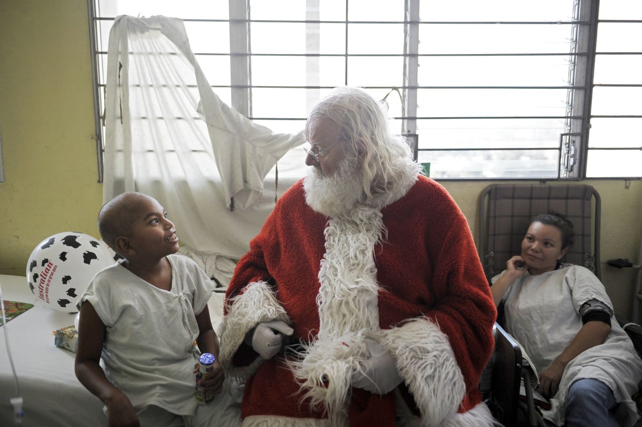 Icelandic philantropist Einar Sveinsson, dressed as Santa Claus, speaks with a patient in the oncology ward during a visit to the Benjamin Bloom National Children's Hospital in San Salvador, El Salvador, on Tuesday, December 11.