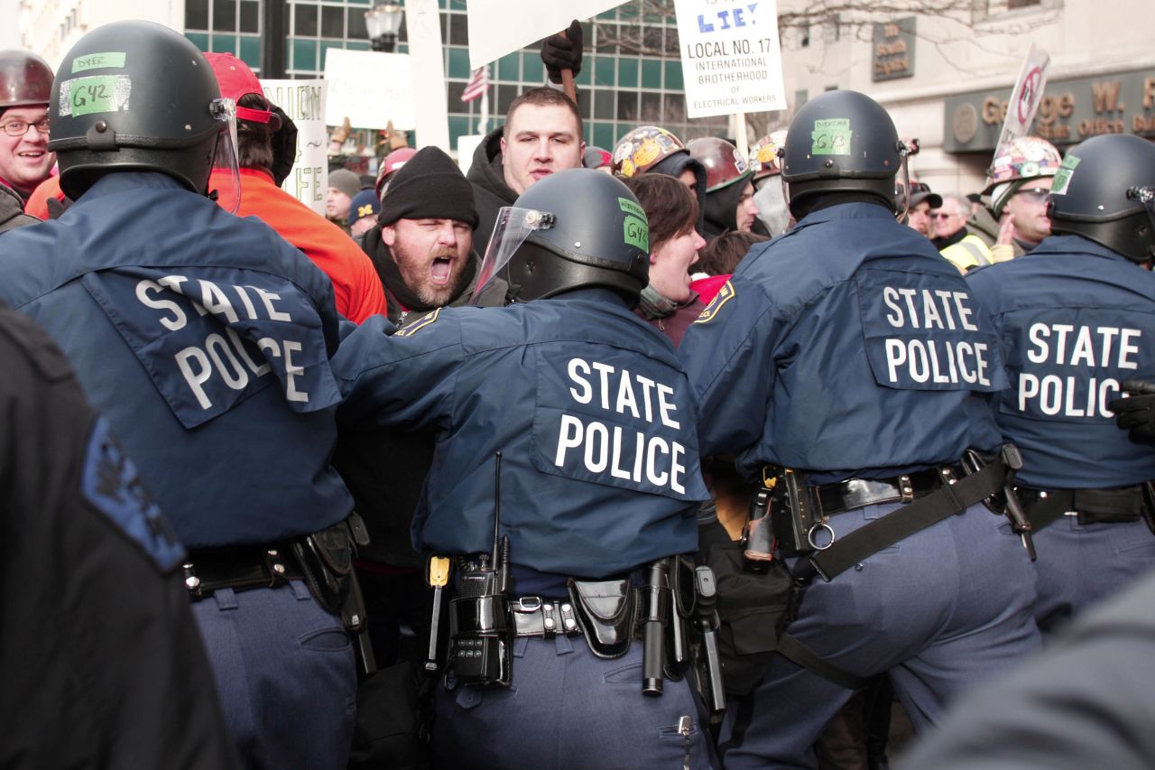 Michigan State Police in riot gear push back against protestors during a rally against right-to-work legislation at the Michigan State Capitol on Tuesday, December 11, in Lansing, Michigan. The House approved two controversial right-to-work measures that would weaken unions' power.